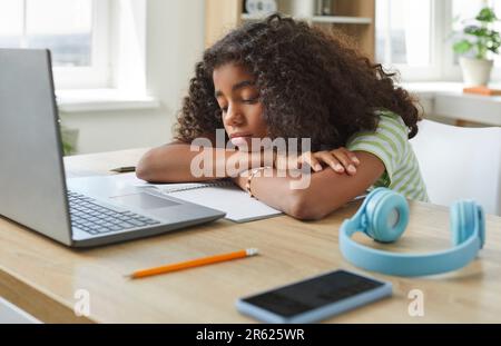 La bambina della scuola si annoia, stanca e triste durante la lezione online sul suo computer portatile Foto Stock