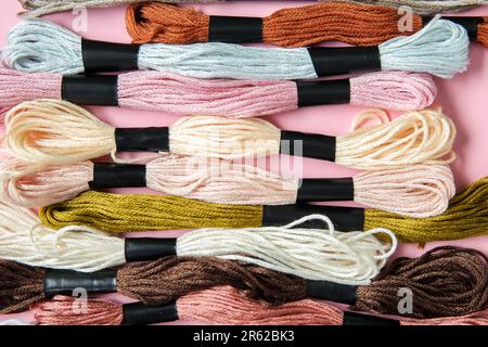 Diversi fili colorati di mouline su sfondo rosa Foto Stock