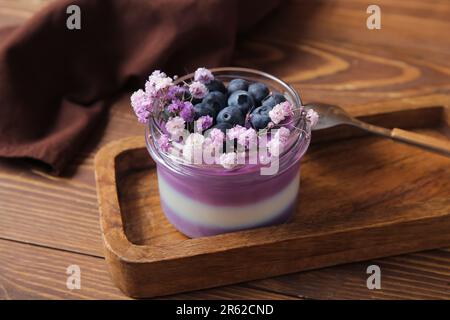 Bicchiere di panna cotta con mirtilli e splendidi fiori di gypsofila su sfondo di legno Foto Stock