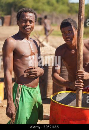 Andranovory, Madagascar - 30 aprile 2019: Due uomini malgasci sconosciuti che estraggono il succo dai frutti in barile grande con il palo di legno - questo deve essere usato Foto Stock