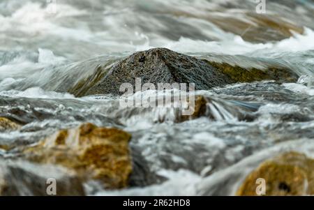 Fiume di sorgente rapido che scorre sulle rocce formando onde d'acqua bianca, dettaglio primo piano - sfondo natura astratto Foto Stock