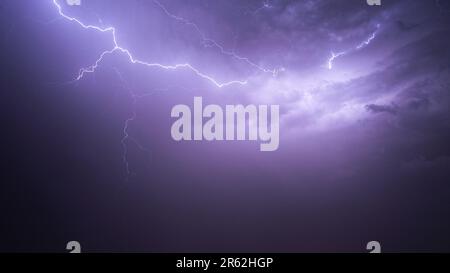 Un'immagine stupefacente di un cielo notturno illuminato da due potenti fulmini che si schiantano verso il basso Foto Stock