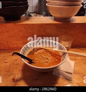 Immagine ravvicinata di un recipiente di ramen con due bacchette appoggiate sul piano di appoggio Foto Stock
