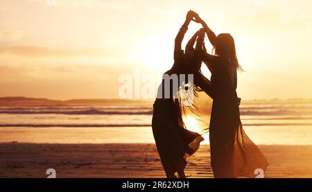 Scorre liberamente e amorevolmente con la vita. due giovani donne trascorrono la giornata in spiaggia al tramonto. Foto Stock