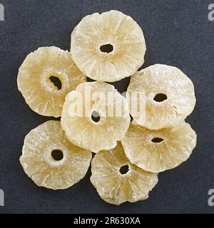 Fette di ananas candite a secco fotografate sopra l'ardesia Foto Stock