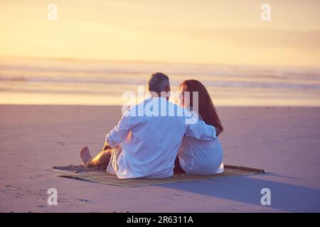 Nella zona priva di stress. una coppia matura che si rilassa insieme sulla spiaggia. Foto Stock