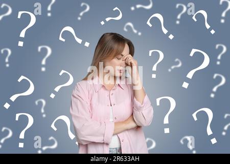 Concetto di amnesia. Donna circondata da punti interrogativi cercando di ricordare qualcosa sullo sfondo a colori Foto Stock