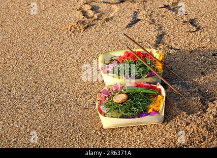 Canang Sari offre agli dei indù sulla spiaggia di Sanur, Bali all'alba. Foto Stock