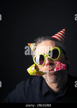 Il carnevale o compleanno ritratto concettuale di un uomo su uno sfondo scuro Foto Stock