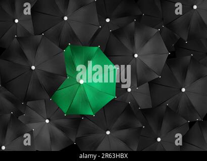Immagine concettuale con un sacco di ombrelli neri e un ombrello verde che si distingue, essere unico Foto Stock