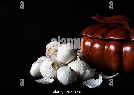 Spicchi freschi Garlics o aglio perla o solo aglio, varietà di Allium ampeloprasum con una scatola di spezie in legno su sfondo nero Foto Stock