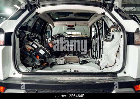 Addetto alla manutenzione dell'auto che installa l'insonorizzante nella vettura Foto Stock