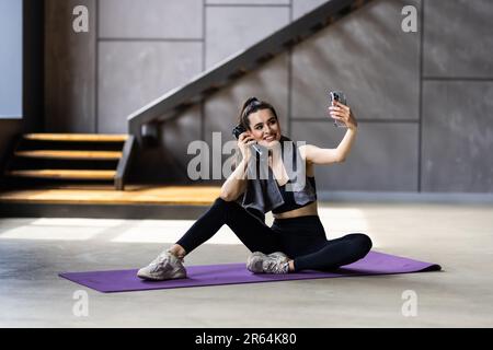 Foto laterale profilo corpo pieno di giovane bella donna pausa pausa sit mat rendere selfie cellulare sportswear casa Foto Stock