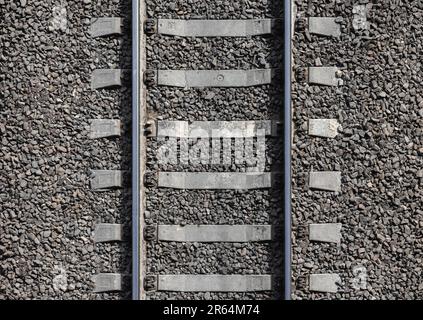 Trama di fondo ferroviario. Guide in acciaio montate su traversine in cemento grigio. Modello fotografico per il trasporto industriale Foto Stock