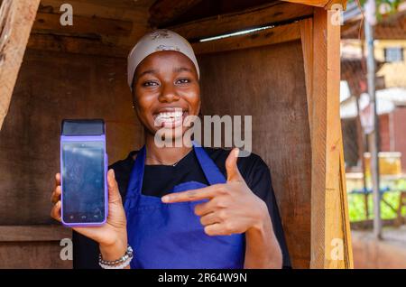 una donna africana che fa uso della sua macchina pos Foto Stock