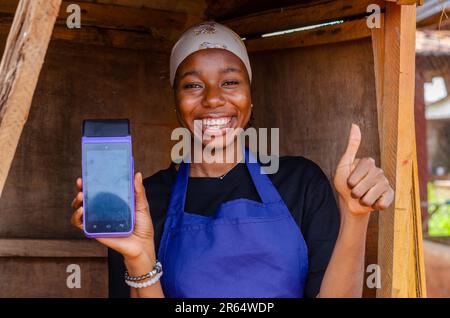 una donna africana che fa uso della sua macchina pos Foto Stock