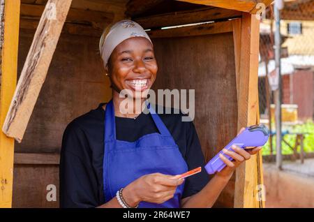 una donna africana che fa uso della sua macchina pos Foto Stock