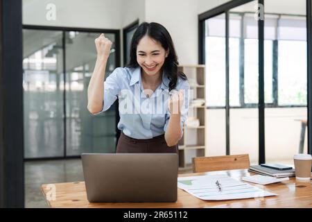 Overjoyed giovane donna d'affari con il laptop che esprime l'eccitazione gioire in ufficio, donna d'affari eccitata ritenere euforica leggere le buone notizie in linea Foto Stock