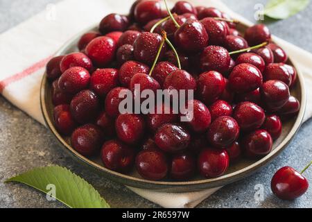 Composizione delle ciliegie dolci su un piatto con gocce d'acqua. Concetto di estate e raccolto. Ciliegio macro. Vegano, vegetariano, crudo Foto Stock