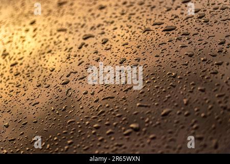 Un'accattivante foto ravvicinata che cattura la texture ipnotica delle gocce d'acqua sulla carrozzeria di un'auto. Foto Stock