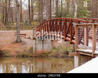 Un piccolo ponte su un tranquillo laghetto nel parco. Foto Stock
