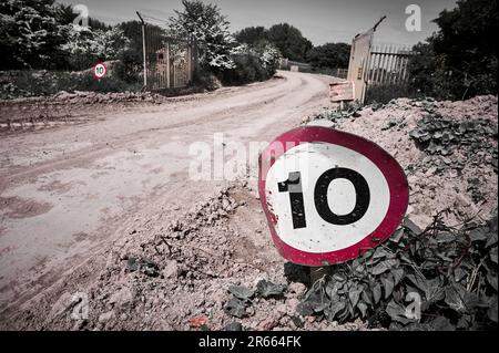 Segnale limite di velocità su strada coperta di fango in cantiere industriale Foto Stock