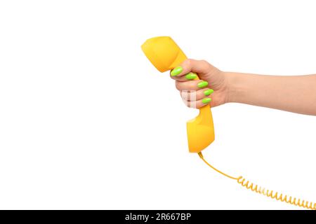 Microtelefono giallo in mano donna con unghie verdi isolate su sfondo bianco. Spazio di copia. Foto Stock