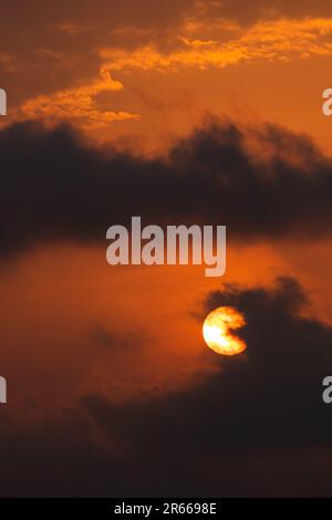 Un tramonto ipnotico sull'orizzonte, con un retrogusto arancione che illumina un cielo tranquillo pieno di colori rossi e rosa. Uno sguardo stupefacente nella natura essere Foto Stock