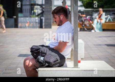 Londra, Regno Unito - 21 giugno 2023 - Heatwave a Londra, un uomo rimane all'ombra per mantenersi fresco al Granary Square di Kings Cross Foto Stock