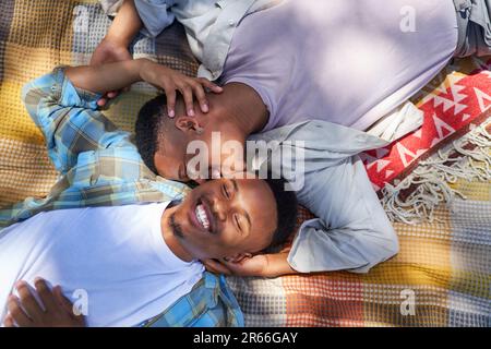 Vista ad angolo alto felice giovane coppia gay maschio baciare su coperta Foto Stock