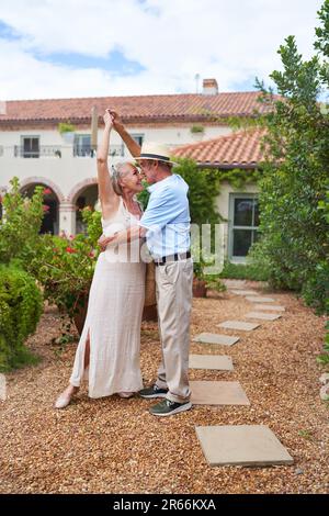 Felice coppia anziana ballare fuori villa in giardino estivo Foto Stock