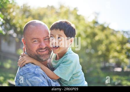 Ritratto felice padre che tiene carino figlio con sindrome di Down Foto Stock