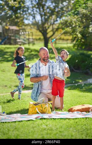 Felice padre e figlio con la sindrome di Down giocando con la bacchetta di bolla Foto Stock