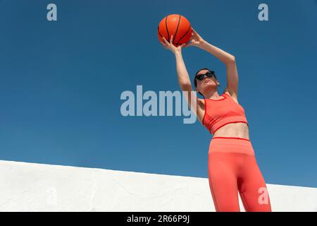 Donna sportiva media adulta che tira cerchi con un basket. Foto Stock