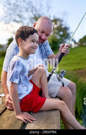 Padre e figlio felice con Down Syndrome pesca sul molo Foto Stock