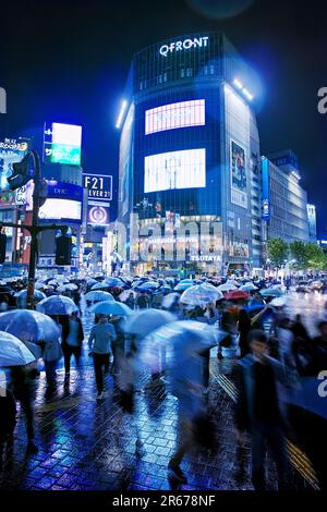 Shibuya Scramble Crossing affollato in una notte piovosa Foto Stock
