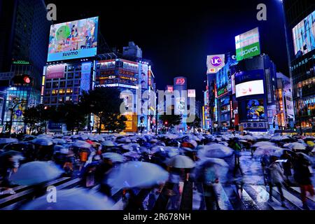Shibuya Scramble Crossing affollato in una notte piovosa Foto Stock