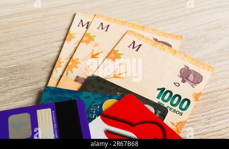 Carte di credito e alcune banconote argentine. Shopping online, concetto di finanze personali. Foto Stock