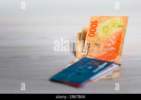 Carte di credito e alcune banconote argentine. Shopping online, concetto di finanze personali. Foto Stock