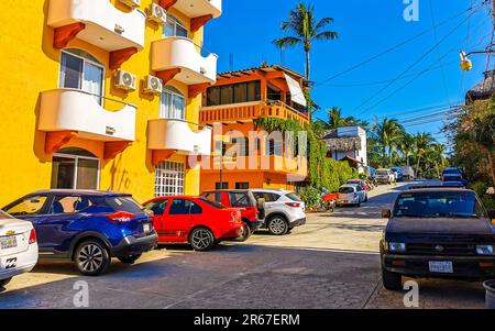 Puerto Escondido Oaxaca Messico 10. Gennaio 2023 strada turistica tipica bella e colorata strada e marciapiede con la vita della città automobili traffico edifici hote Foto Stock