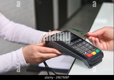 Attenzione selettiva al terminale POS, lettore di carte di credito in mano per la visualizzazione senza contanti dei pagamenti tecnologia NFC Foto Stock