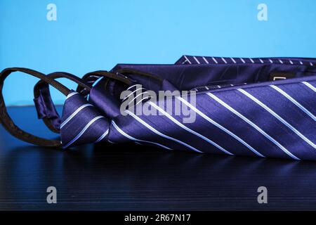 Una borsa viola si trova su un tavolo liscio, con una vibrante cravatta legata intorno ad esso Foto Stock