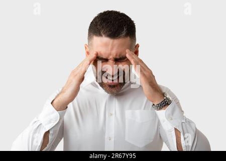 Ritratto di un uomo d'affari di mezza età stressato che ha mal di testa, strofinando templi, che soffrono di emicrania, sfondo chiaro Foto Stock