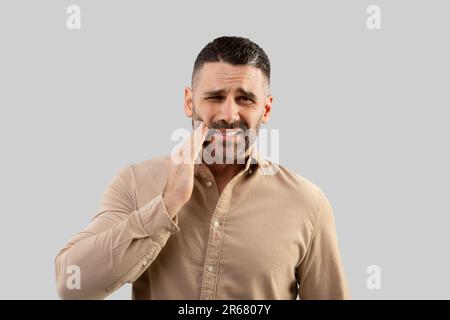 Infelice uomo d'affari di mezza età che soffre di mal di denti, problemi gengivali, che soffrono di dolore dentale Foto Stock