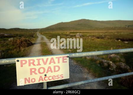 Primo piano di cartello strada privata, nessun accesso alla recinzione con strada di campagna e montagne sullo sfondo al Connemara National Park, contea di Galway, Irlanda Foto Stock