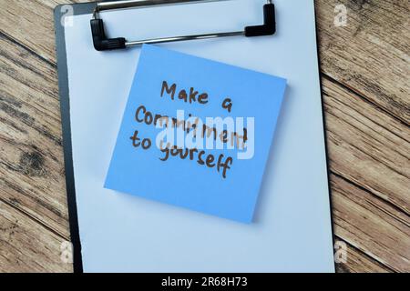 Concetto di fare un impegno a sé stessi scrivere su note appiccicose isolato su tavolo di legno. Foto Stock