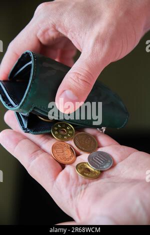 Mano che tiene un portafoglio con monete di yen. Foto Stock