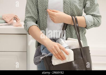 Donna che mette il pannolino nel sacchetto della madre all'interno, primo piano Foto Stock