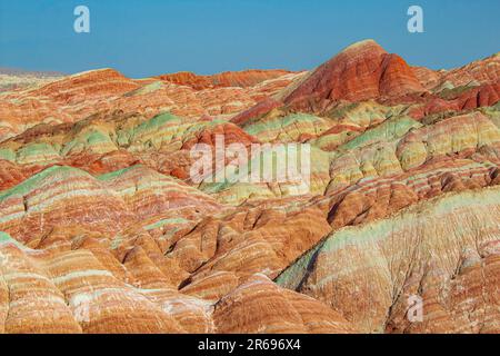 Vista aerea dall'alto verso il basso sulle montagne di Zhangye Rainbow con motivi colorati, spazio di copia per il testo, sfondo Foto Stock