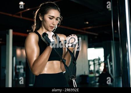 Donna sportiva che si esercita sulla multistazione in palestra per i muscoli delle braccia e delle spalle. Fitness in palestra. Foto Stock